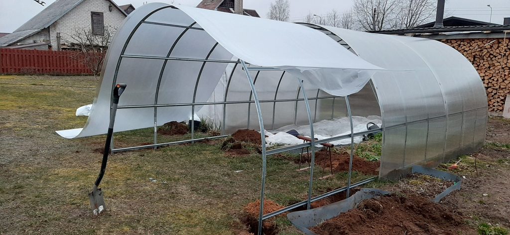 Polycarbonate sheet laid over greenhouse extension frame