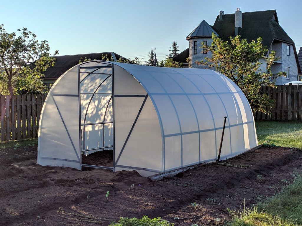Arched greenhouse with translucent polycarbonate covering fitted over the roof, sides and end walls.
